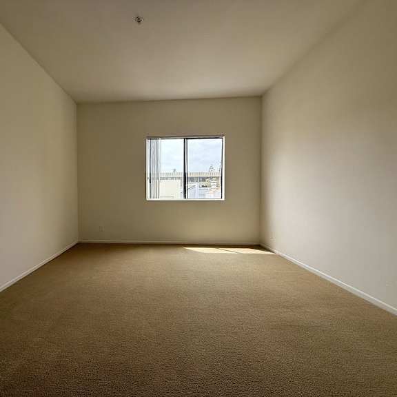 Thumbnail 6 of 29 A room with a carpeted floor and a window.