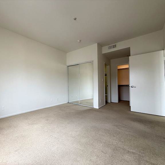 Thumbnail 10 of 29 A spacious room with white walls and carpeted floor.