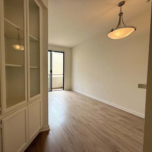 Thumbnail 6 of 39 A room with a wooden floor and a hanging light fixture.