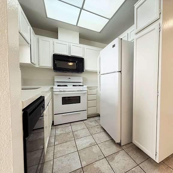 Thumbnail 13 of 53 A kitchen with white appliances and cabinets.