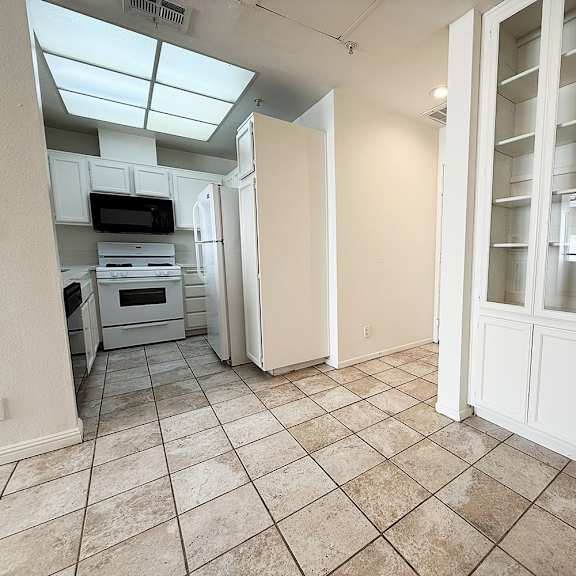 Thumbnail 2 of 53 A kitchen with white cabinets and a microwave.