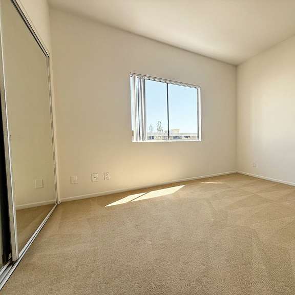 Thumbnail 20 of 53 A room with a large window and carpeted floor.