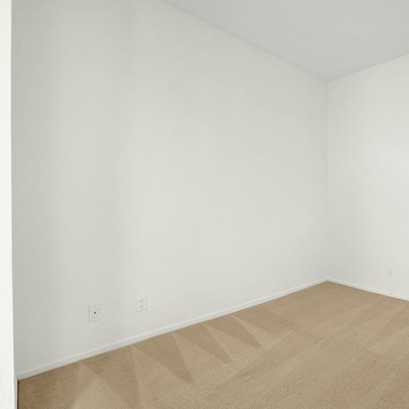 Thumbnail 9 of 13 A room with a tan carpet and white walls.