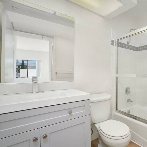Thumbnail 22 of 29 A white bathroom with a toilet, sink, and shower.