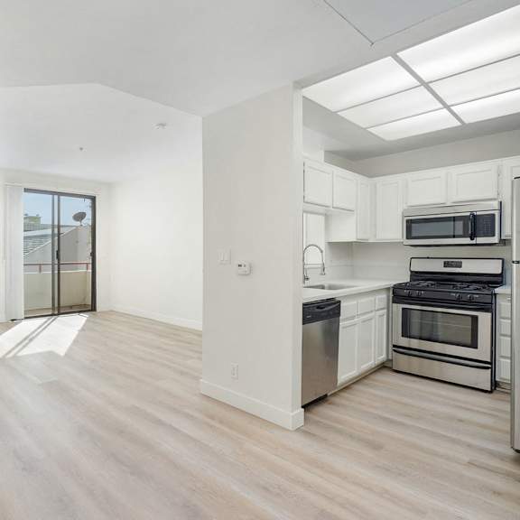 Thumbnail 19 of 29 A kitchen with white cabinets and a wooden floor.