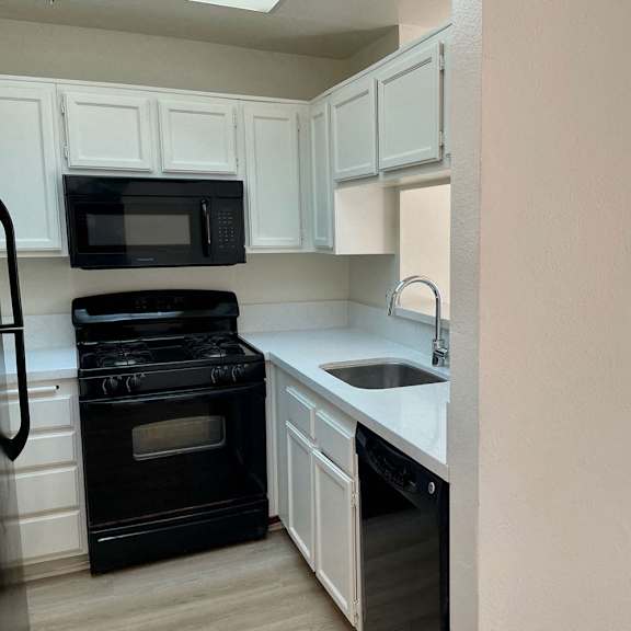 Thumbnail 21 of 26 A black stove and oven in a kitchen with white cabinets.