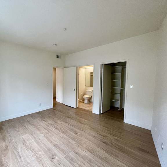 Thumbnail 32 of 53 A room with a wooden floor and white walls.