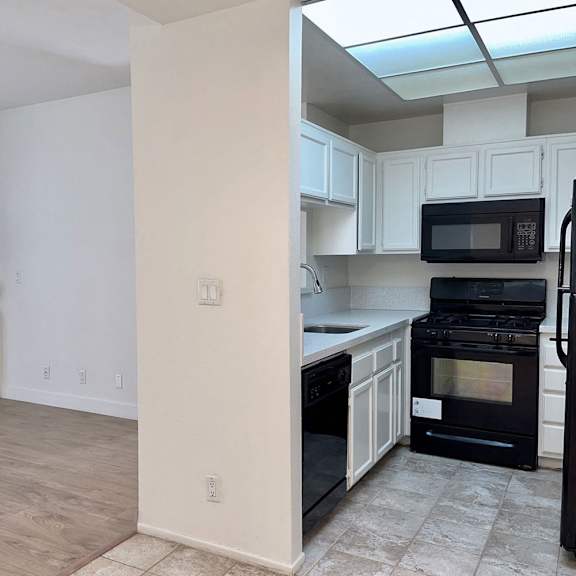 Thumbnail 26 of 53 A kitchen with black appliances and white cabinets.