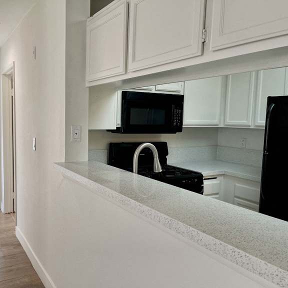 Thumbnail 28 of 53 A kitchen with black appliances and white cabinets.