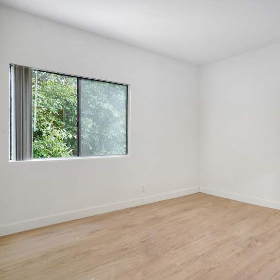Thumbnail 11 of 21 Empty room with a window and wooden floor.
