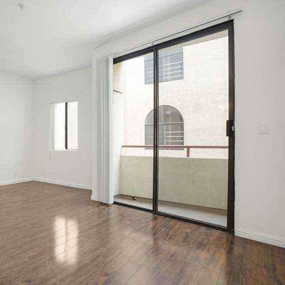 Thumbnail 16 of 39 A room with a sliding glass door and wooden flooring.