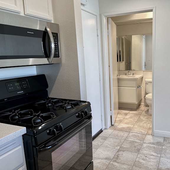 Thumbnail 23 of 39 A kitchen with a black stove top oven and a white refrigerator.