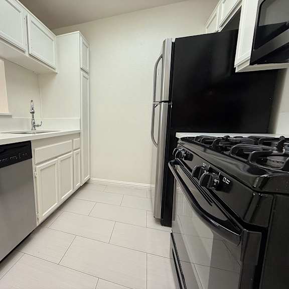 Thumbnail 25 of 39 A kitchen with a black fridge and stove.