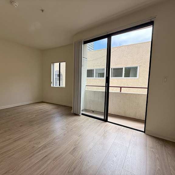 Thumbnail 26 of 39 Empty room with wooden flooring and sliding glass doors.