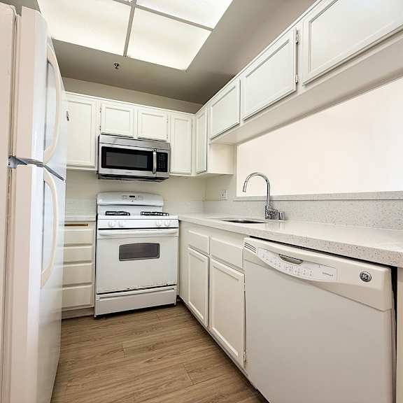 Thumbnail 25 of 26 A kitchen with white appliances and cabinets.