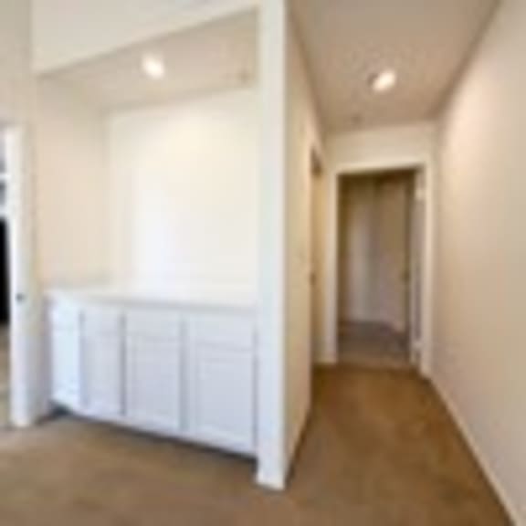 Thumbnail 46 of 53 A long white hallway with a white cabinet on the left.