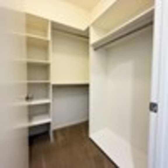 Thumbnail 48 of 53 A white hallway with a door on the right and a shelf on the left.