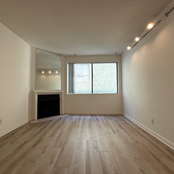 Thumbnail 9 of 26 A large empty room with a fireplace and a window.