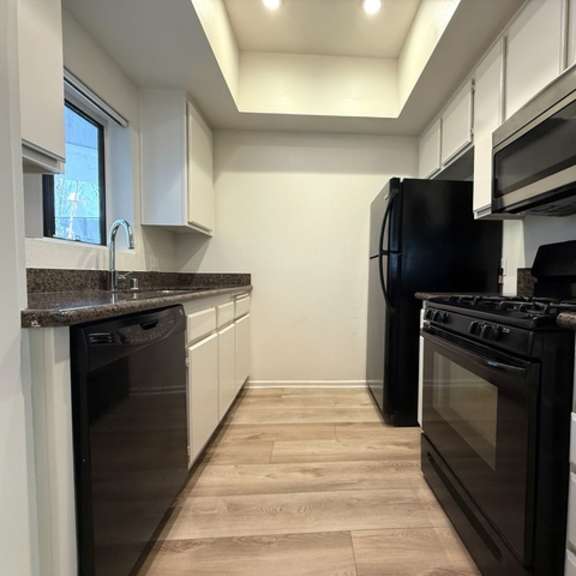 Thumbnail 2 of 26 A kitchen with black appliances and white cabinets.