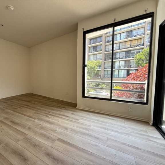 Thumbnail 5 of 26 A room with a large window and wooden flooring.
