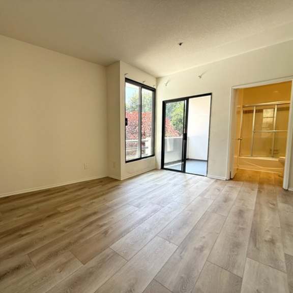 Thumbnail 7 of 26 A room with wooden flooring and a sliding glass door.