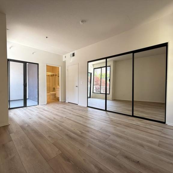 Thumbnail 3 of 26 A room with wooden floors and a large mirror on the wall.