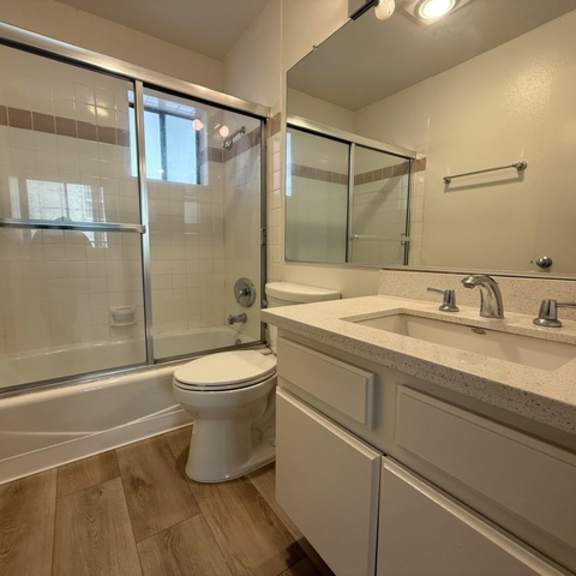 Thumbnail 16 of 26 A white toilet sits in a bathroom with a walk-in shower.