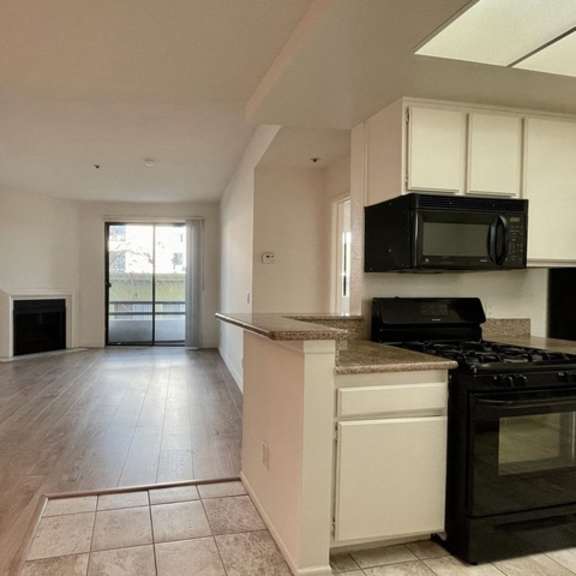 Thumbnail 7 of 11 A kitchen with black appliances and white cabinets.