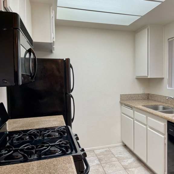Thumbnail 4 of 11 A kitchen with a black stove top oven and white cabinets.