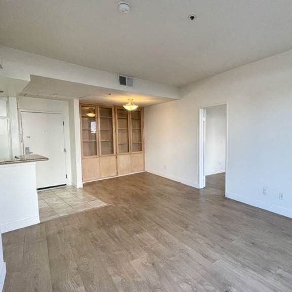 Thumbnail 11 of 11 A spacious room with wooden flooring and white walls.