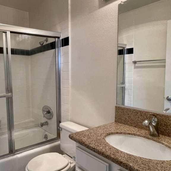 Thumbnail 6 of 11 A bathroom with a toilet, sink, and shower.