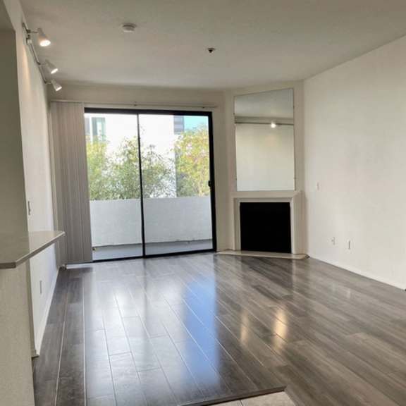 Thumbnail 5 of 11 A spacious room with a glass door leading to a balcony.