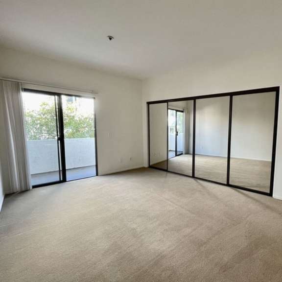 Thumbnail 8 of 11 A spacious room with a carpeted floor and sliding glass doors.