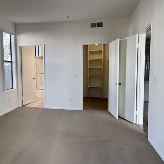 Thumbnail 10 of 11 A large empty room with a door on the left and a shelving unit on the right.