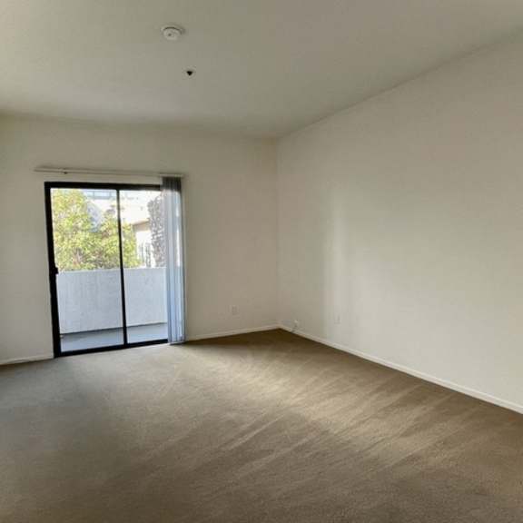 Thumbnail 9 of 11 A room with a sliding glass door leading to a balcony.