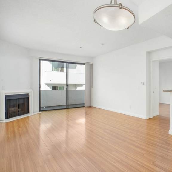 Thumbnail 14 of 14 A spacious kitchen and living room with hardwood floors and white cabinetry.