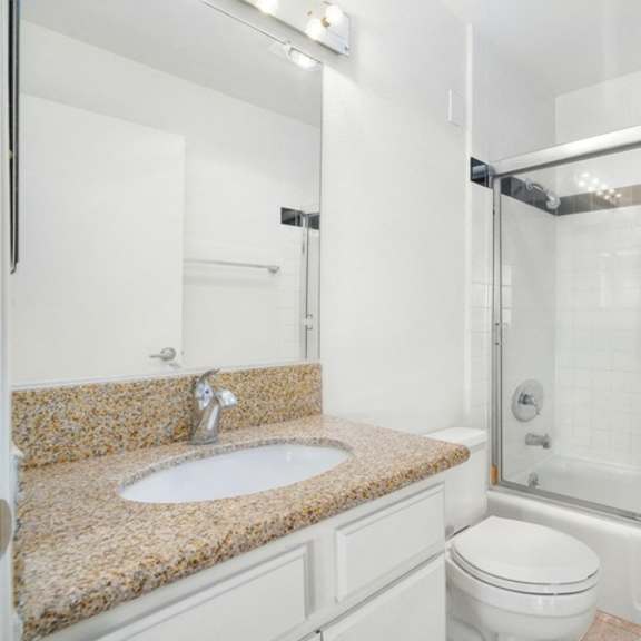 Thumbnail 5 of 14 A bathroom with a sink, toilet, and shower.