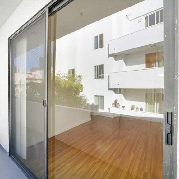 Thumbnail 4 of 14 A balcony with a glass door and a wooden floor.