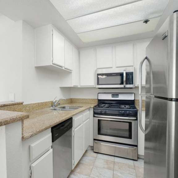 Thumbnail 6 of 14 A kitchen with granite countertops and stainless steel appliances.