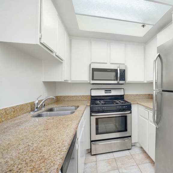 Thumbnail 10 of 14 A kitchen with a stainless steel refrigerator, microwave, oven, and sink.