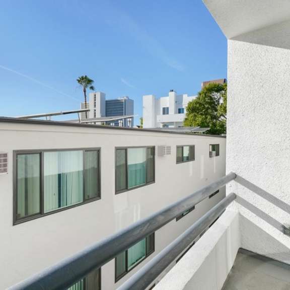 Thumbnail 5 of 17 A white building with a balcony overlooking a cityscape.
