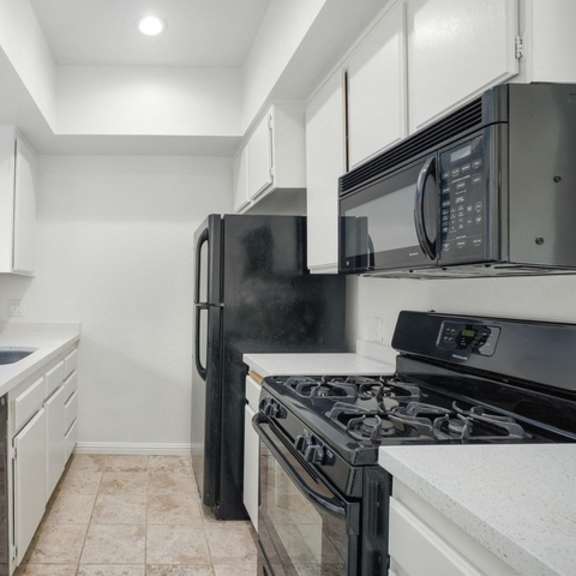 Thumbnail 8 of 17 A kitchen with black appliances and white cabinets.