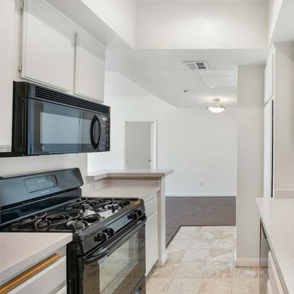 Thumbnail 7 of 17 A kitchen with a black stove top oven and a black microwave.