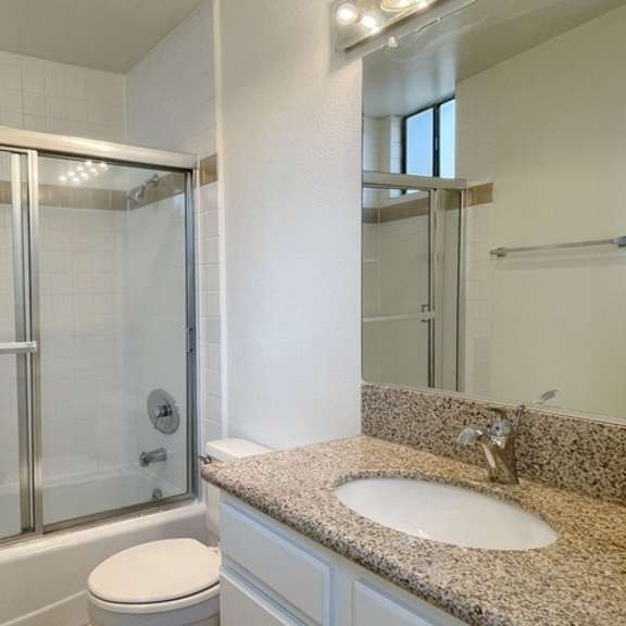 Thumbnail 5 of 18 A bathroom with a toilet, sink, and shower.