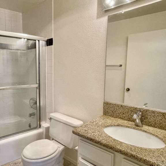 Thumbnail 3 of 8 A white toilet sits next to a sink in a bathroom.