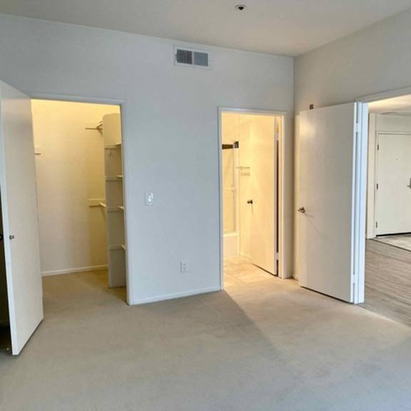 Thumbnail 8 of 8 A white room with three doors and a mirror.