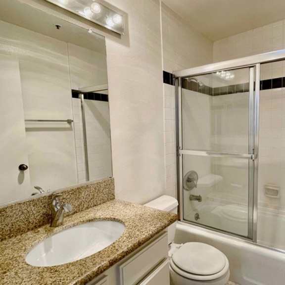 Thumbnail 6 of 8 A bathroom with a sink, toilet, and shower.