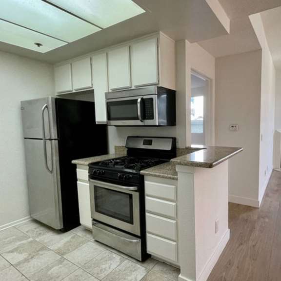 Thumbnail 19 of 26 A kitchen with a refrigerator, oven, microwave, and stove.
