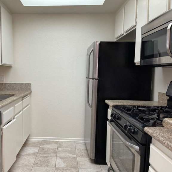 Thumbnail 18 of 26 A kitchen with black appliances and white cabinets.