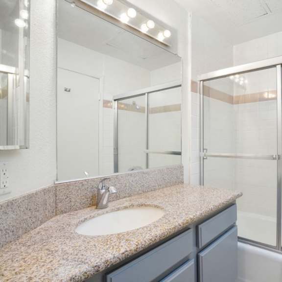 Thumbnail 3 of 11 A bathroom with a sink, mirror, and shower.